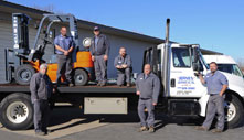 team of service men standing on and around service vehicle